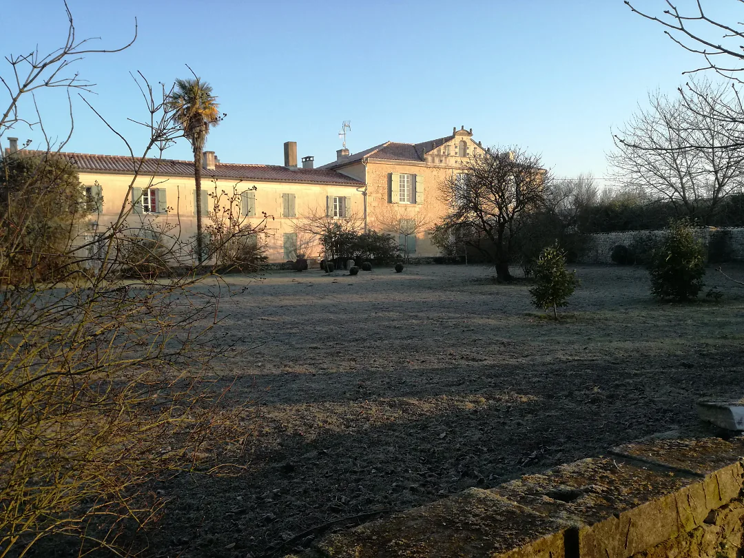 La façade du logis derrière la pelouse gelée, sous un ciel d'hiver