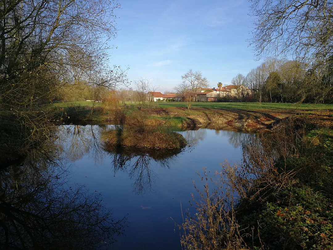 Bras de rivière bordé de prés, le village au loin
