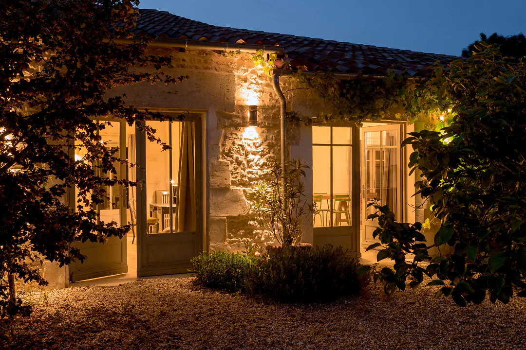 La façade de Bons Bois éclairée à la nuit tombée, portes-fenêtres allumées sur le jardin
