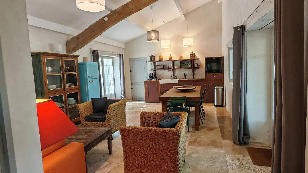 Pièce à vivre de Bons Bois – Petite Champagne sous poutre apparente, canapé orange et cuisine ouverte