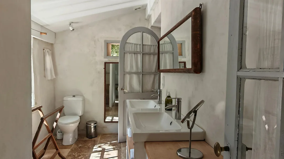 Salle d'eau de Bons Bois, vasque et miroir arrondi sous la charpente blanche