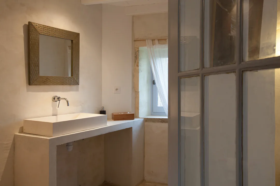 Seconde salle d'eau de Bons Bois derrière une verrière, vasque maçonnée et miroir en bois