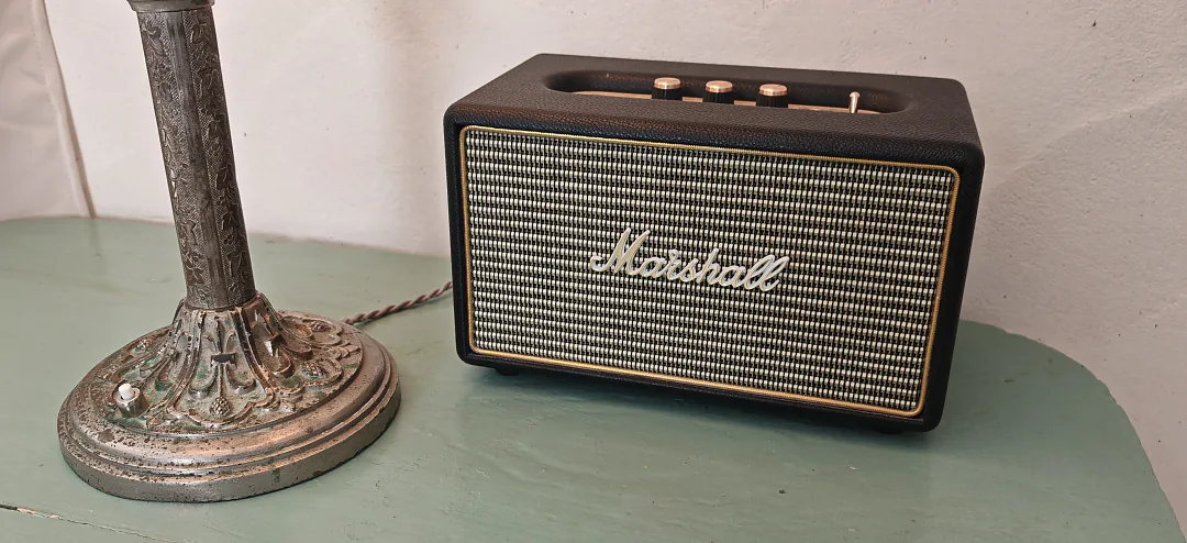 Enceinte Marshall posée sur un guéridon vert d'eau, à côté d'un pied de lampe ancien