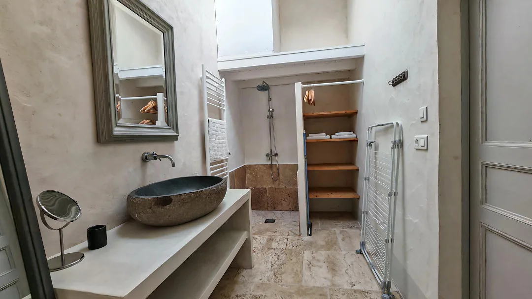 Salle d'eau de Borderies, vasque en pierre sur tablette maçonnée, grand miroir et douche à l'italienne