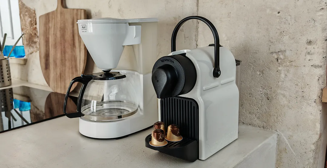 Cafetière filtre et machine à capsules sur le plan de travail, planche à découper en bois