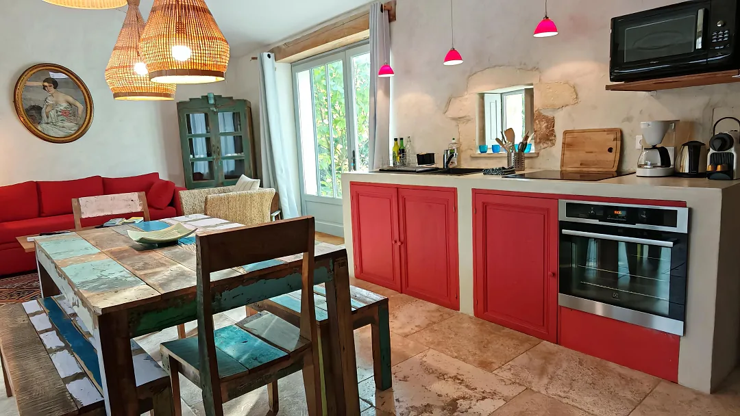 Cuisine ouverte de Fins Bois, façades rouges, four encastré et grande table aux bois colorés