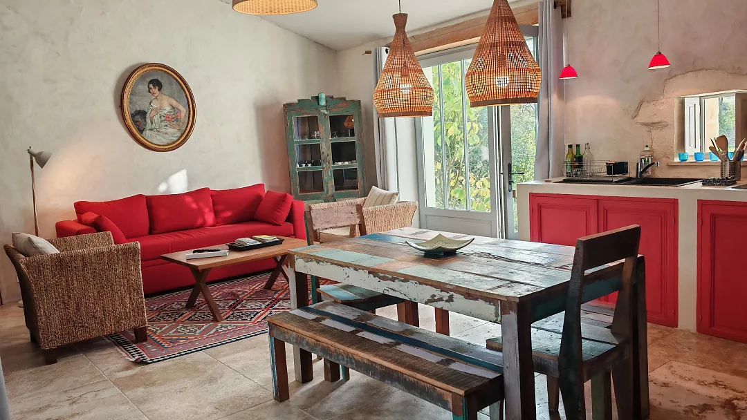 Séjour de Fins Bois, canapé rouge, table de ferme et cuisine ouverte à façades rouges