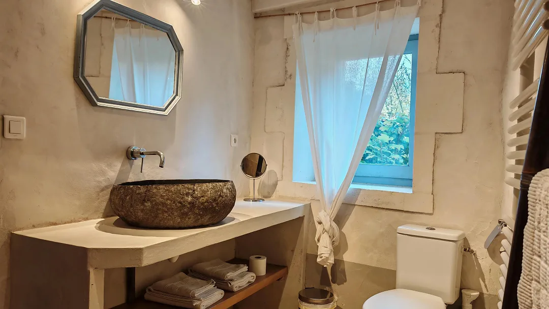Salle d'eau de Fins Bois, vasque en pierre sur plan de travail et miroir octogonal