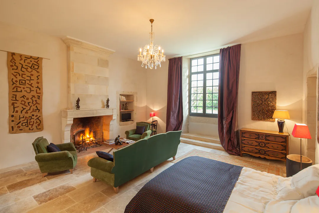 Séjour-chambre de Grande Champagne, feu dans la cheminée de pierre et lustre à pampilles