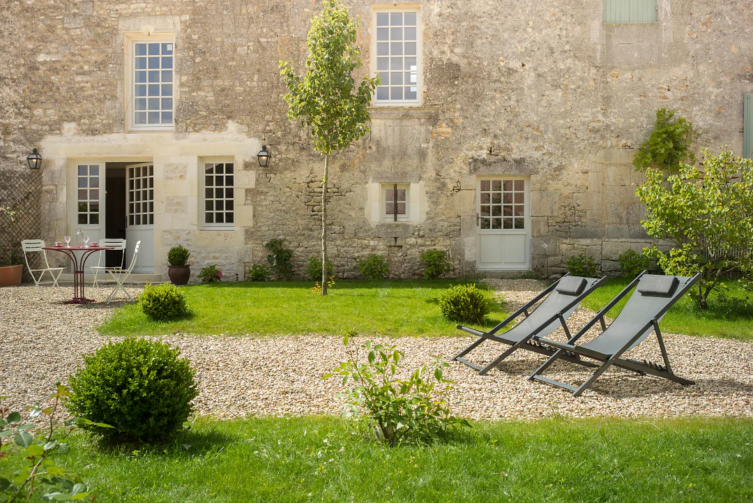 Le jardin clos de Grande Champagne, transats sur le gravier devant la façade de pierre