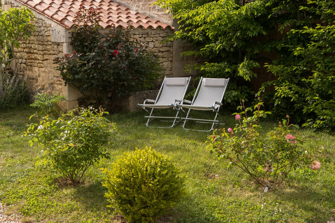 Transats à l'ombre du mur de pierre, dans le jardin clos de Grande Champagne