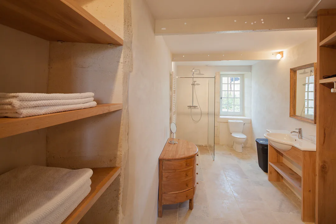 Salle d'eau de Grande Champagne, étagères de bois, douche à l'italienne et linge plié